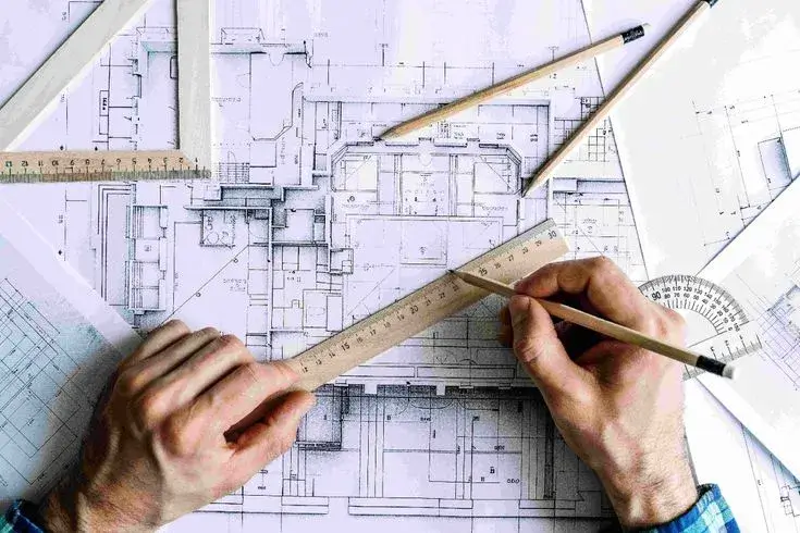 A designer sketching on a tablet with architectural plans in the background